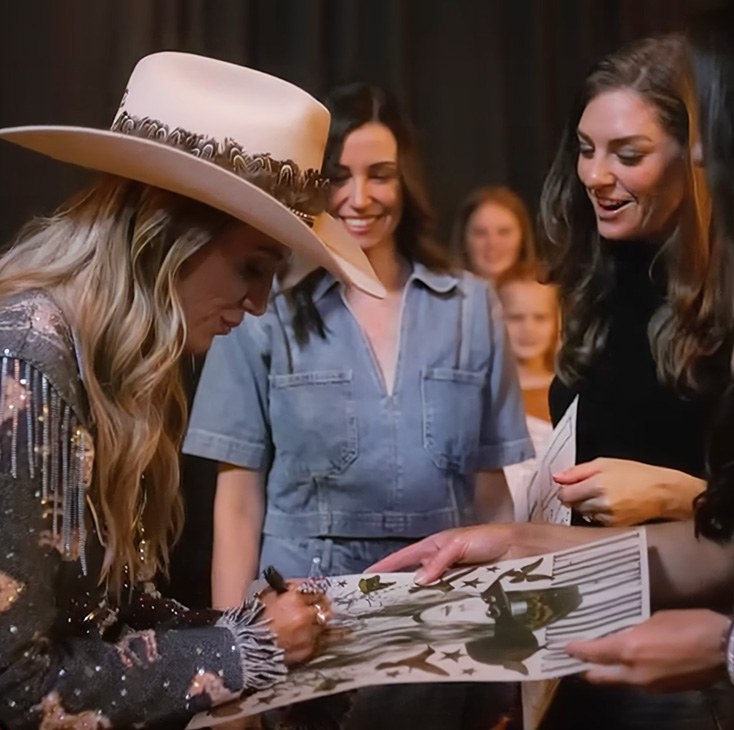 Artist signing a poster for fans at a Ford Music meet and greet.